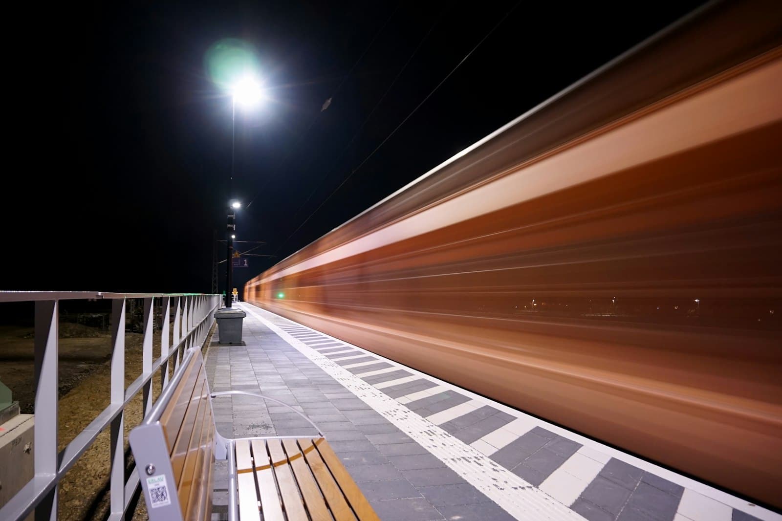 A night train streaking past an empty station platform in a long exposure